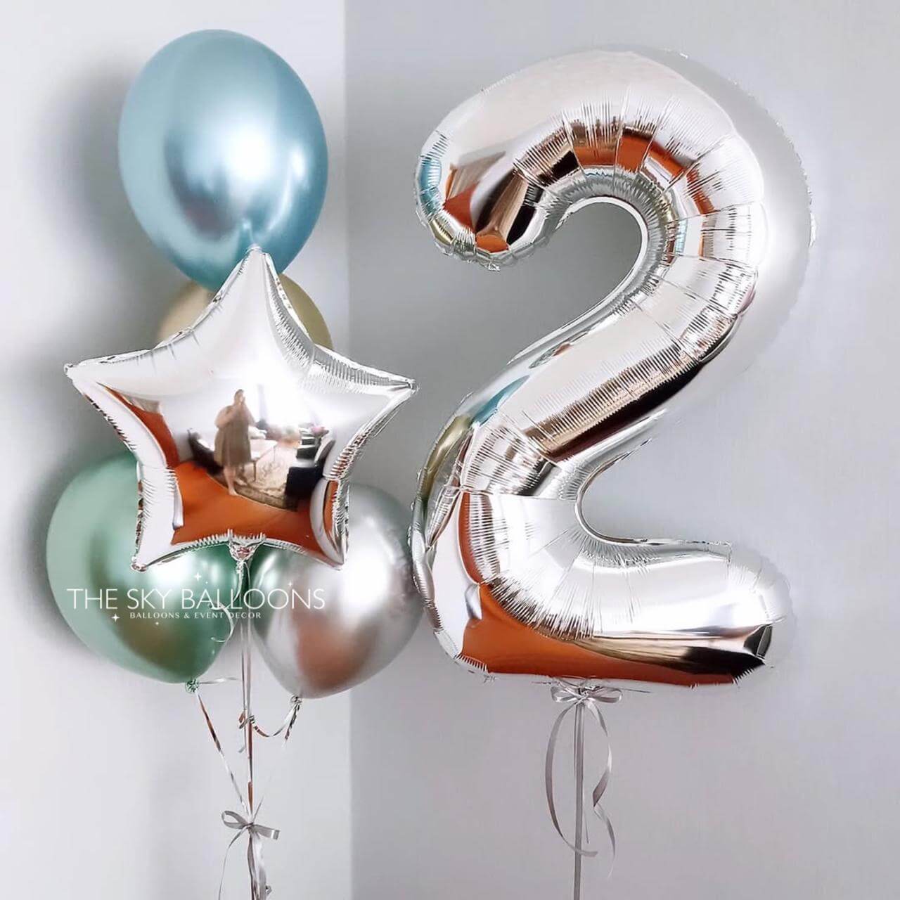 Silver number '2' balloon with star and round balloons on a light gray background