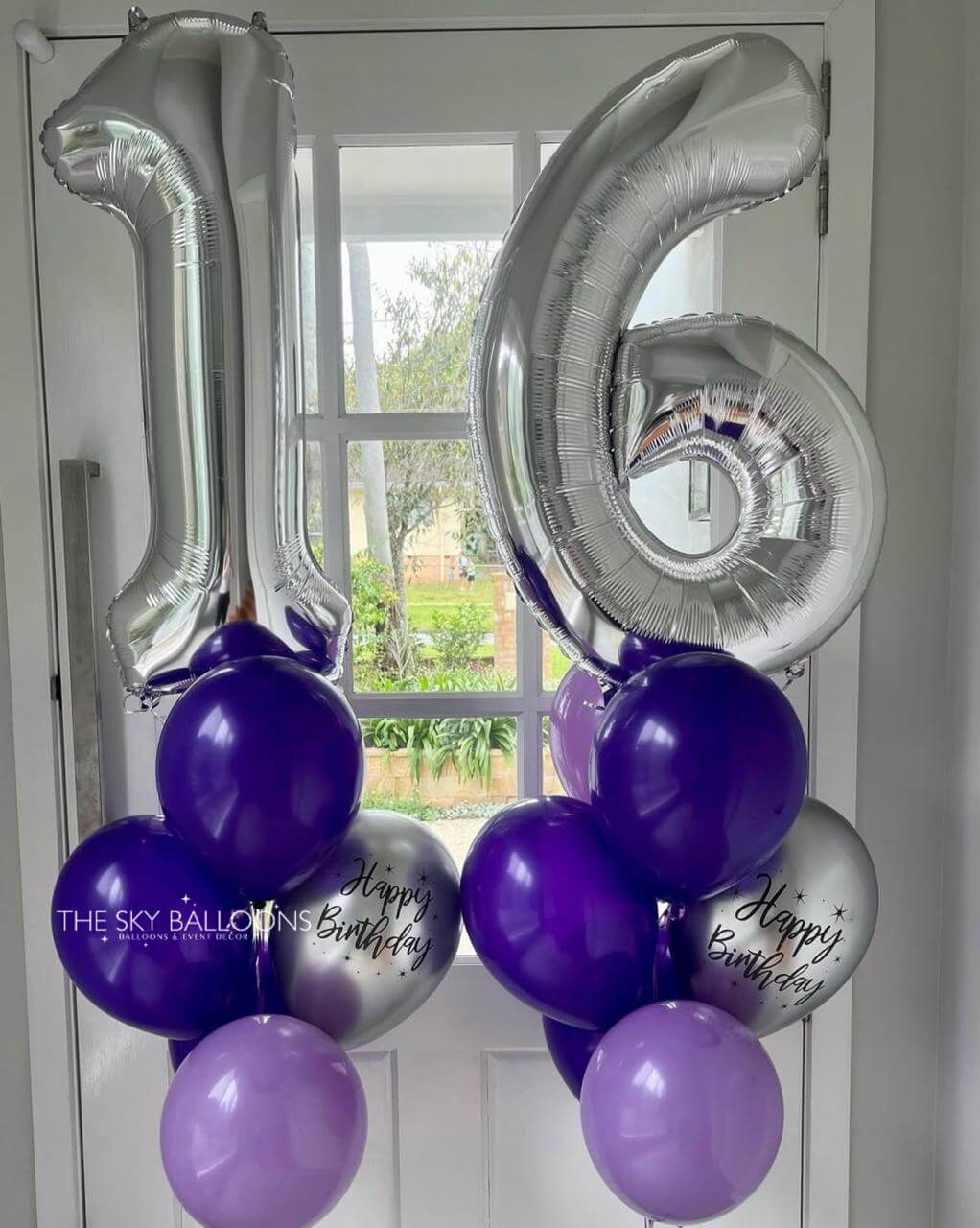 Silver number balloons spelling '16' with purple and gray balloons against a window background.