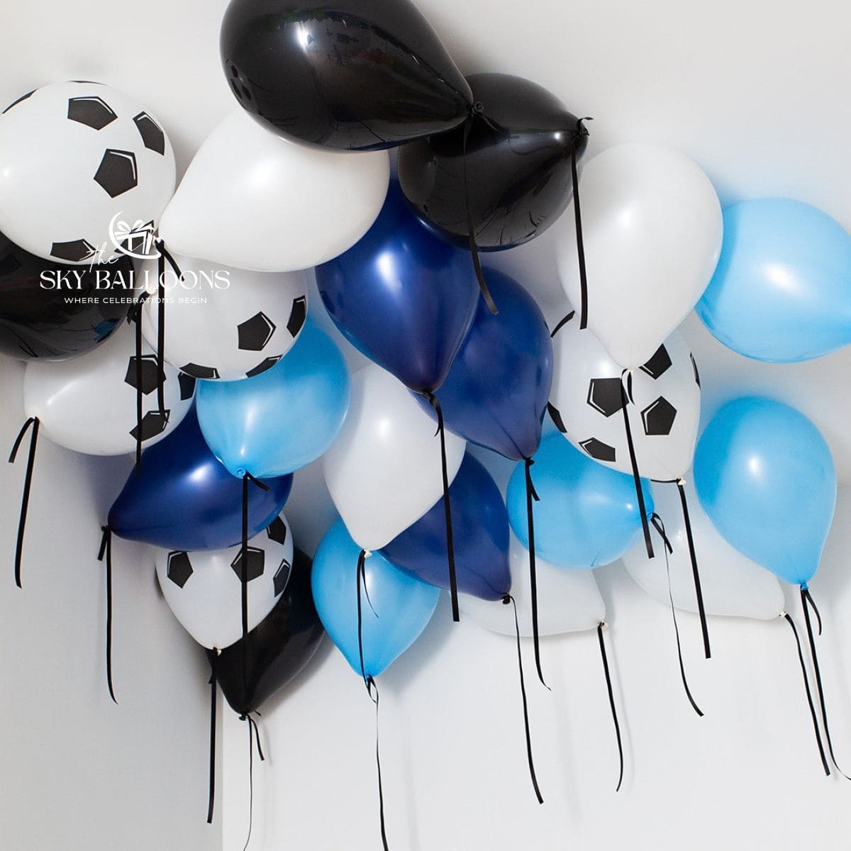 Blue, white and black ceiling balloons with football-print balloons and hanging black ribbons.

