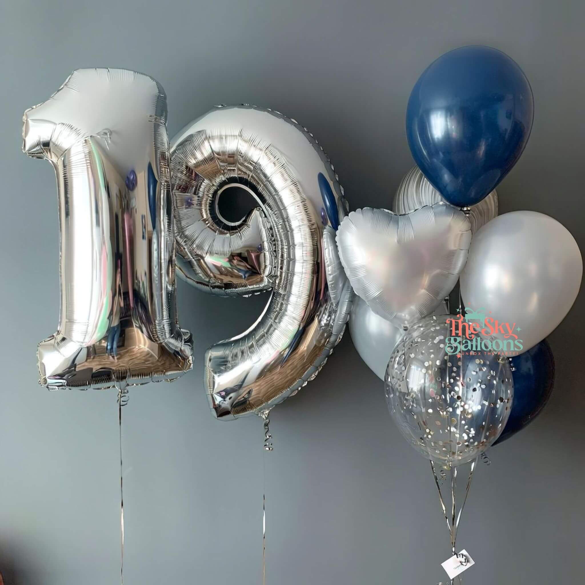 Silver number 19 balloon and other balloons against a gray background