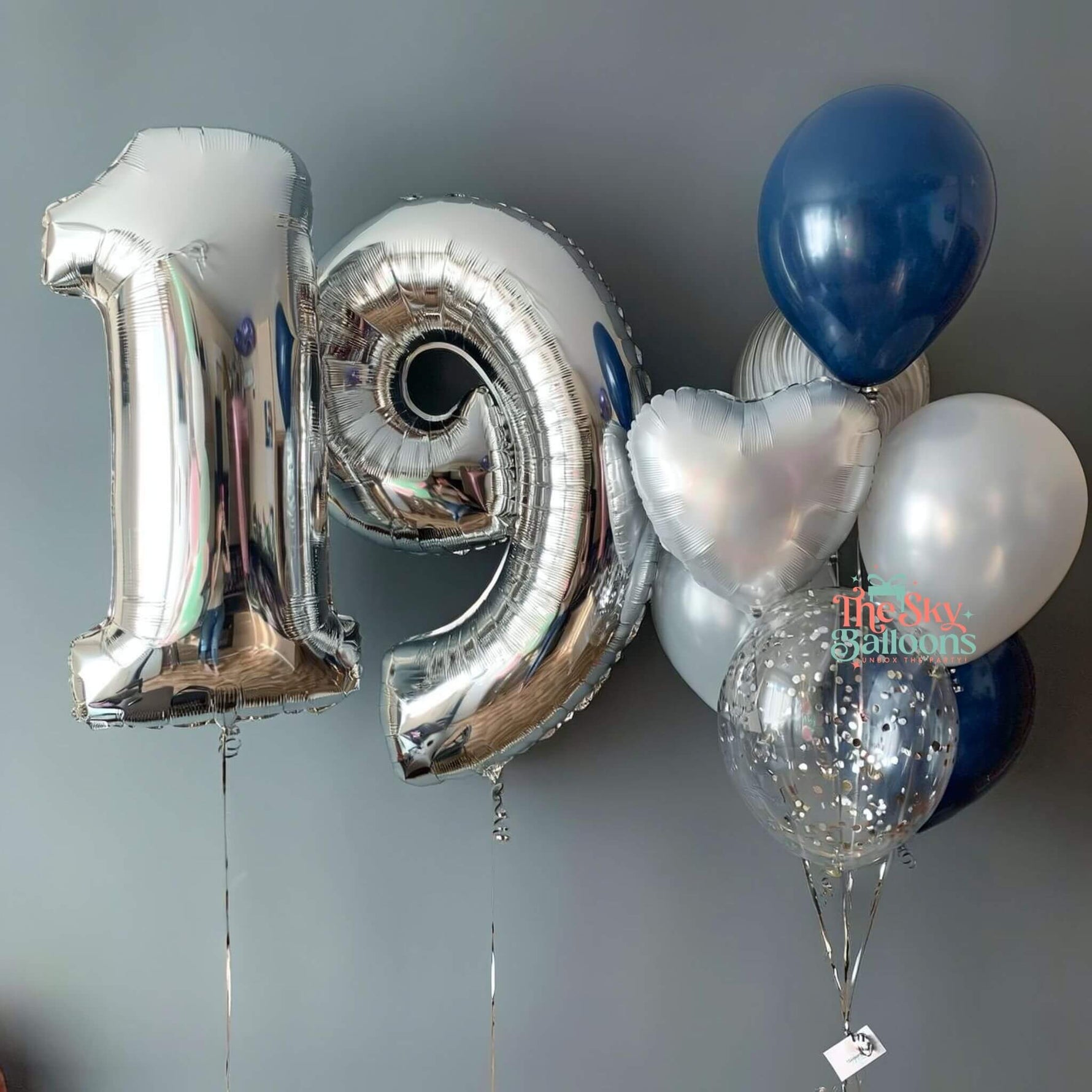 Silver number 19 balloon and other balloons against a gray background