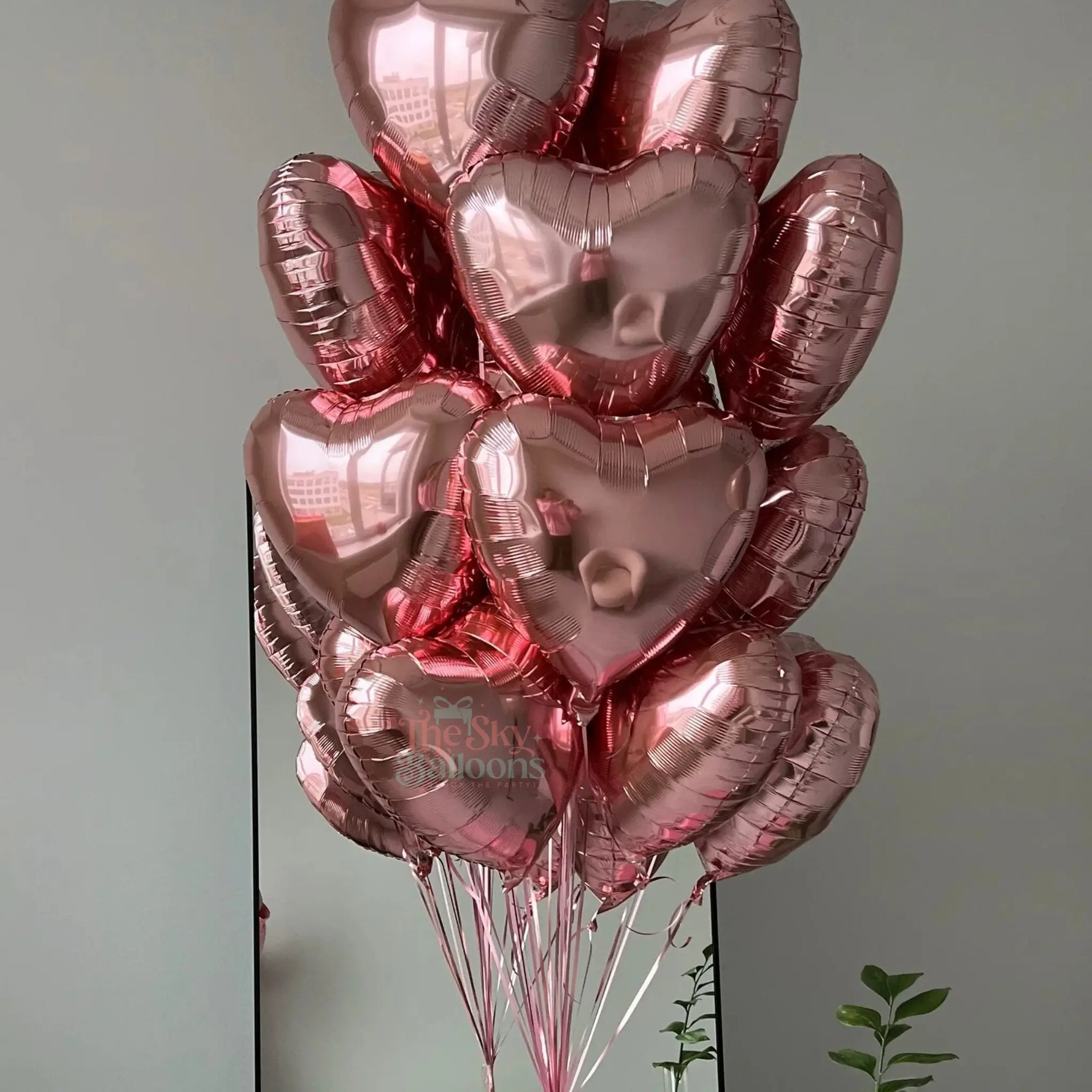 Bouquet of pink heart-shaped balloons against a plain background
