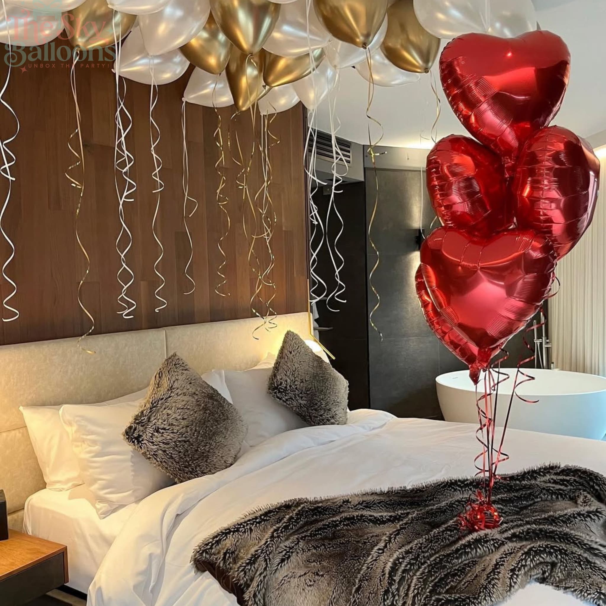 Decorative balloons in a bedroom setting with red heart-shaped balloons on a bed.