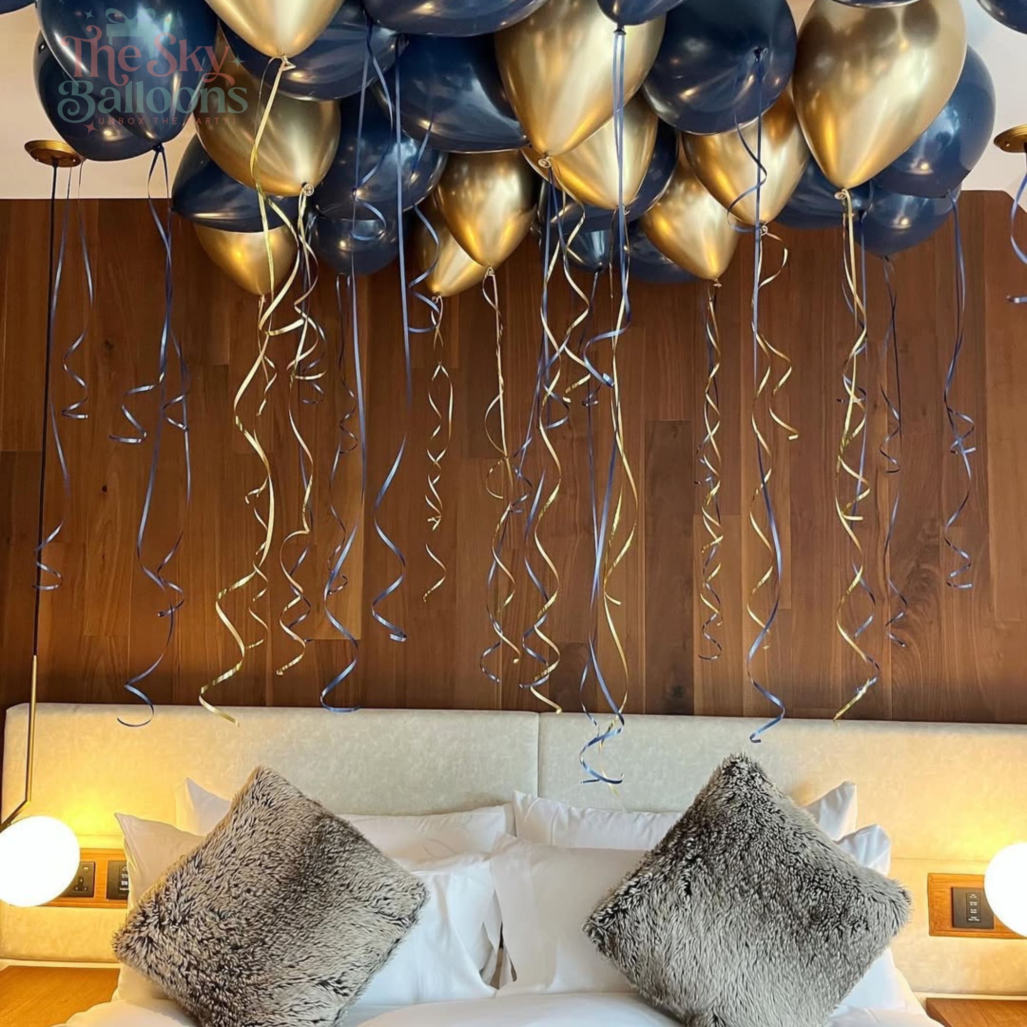Decorative balloons and ribbons hanging above a bed with pillows.