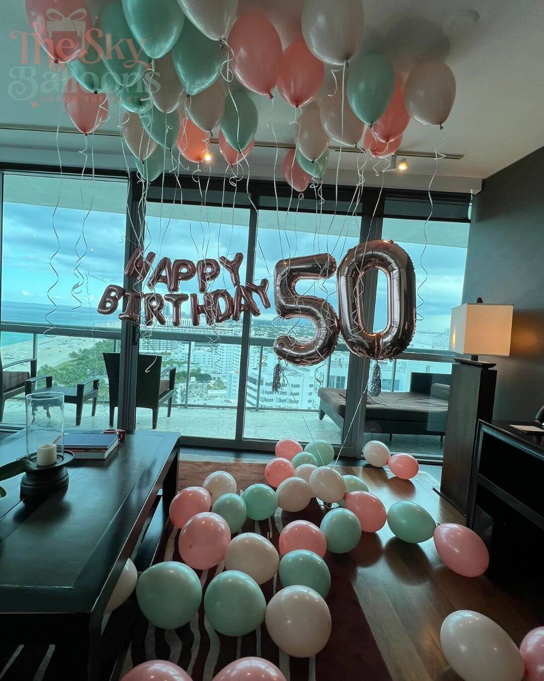 Decorative balloons with 'Happy Birthday 50' in a room with large windows.