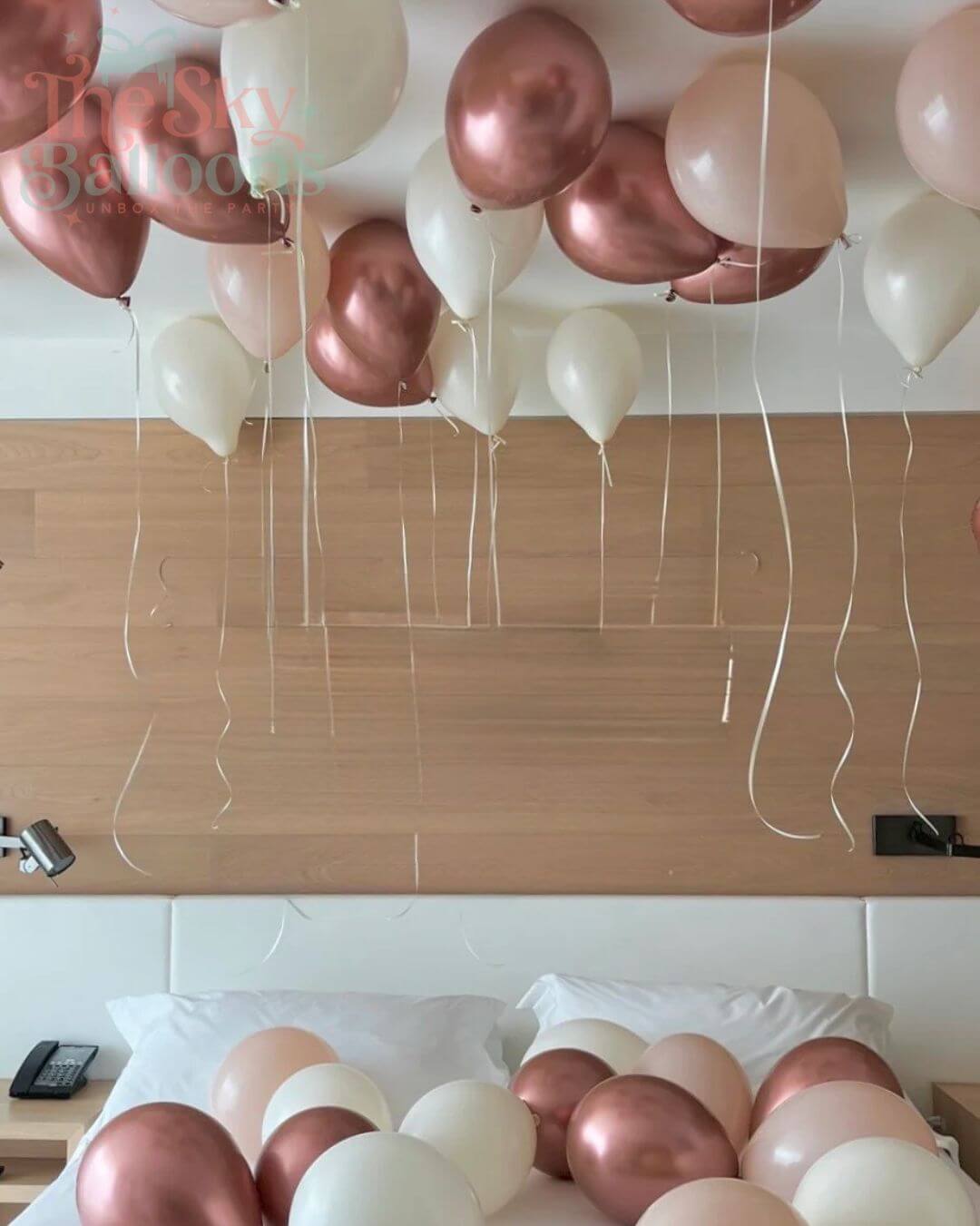 Decorative arrangement of balloons in rose gold and white on a ceiling and surface.
