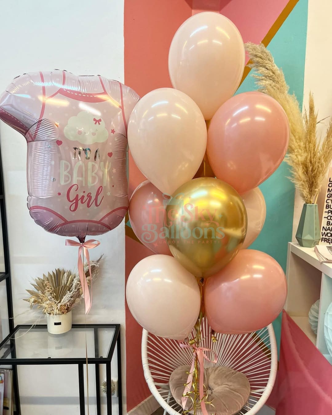 Decorative balloon arrangement with 'Baby Girl' balloon in a room setting.