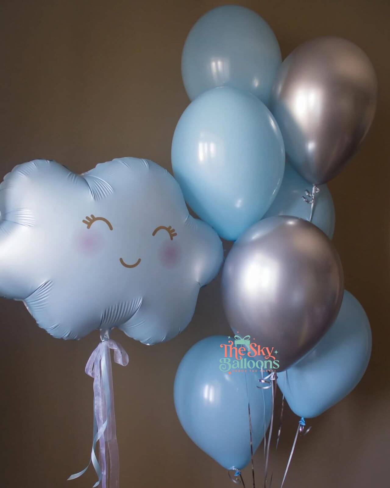 Bouquet of balloons including a cloud-shaped balloon with a smiley face on a brown background.