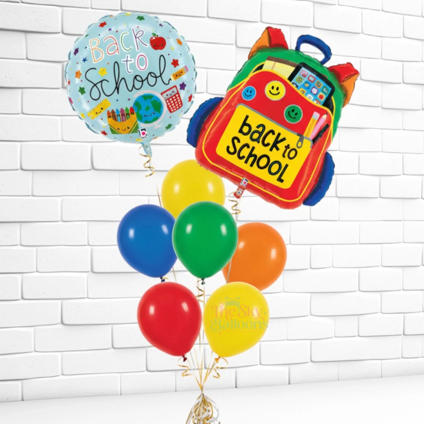 Colorful 'Back to School' balloons with a backpack-shaped balloon against a white brick wall.