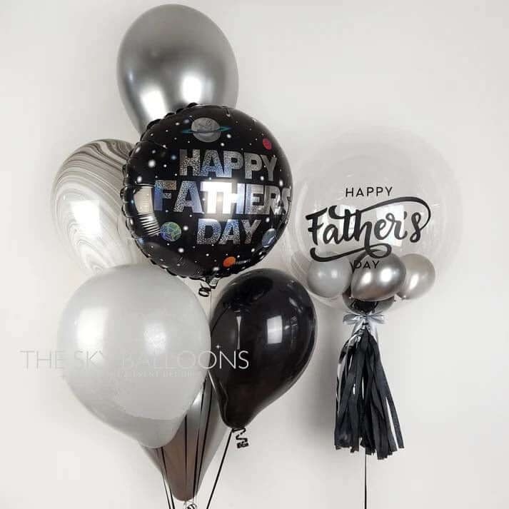 A bouquet of latex and foil balloons with 'Happy Father's Day' text and decorative elements, including a customized balloon with a small inside balloon.