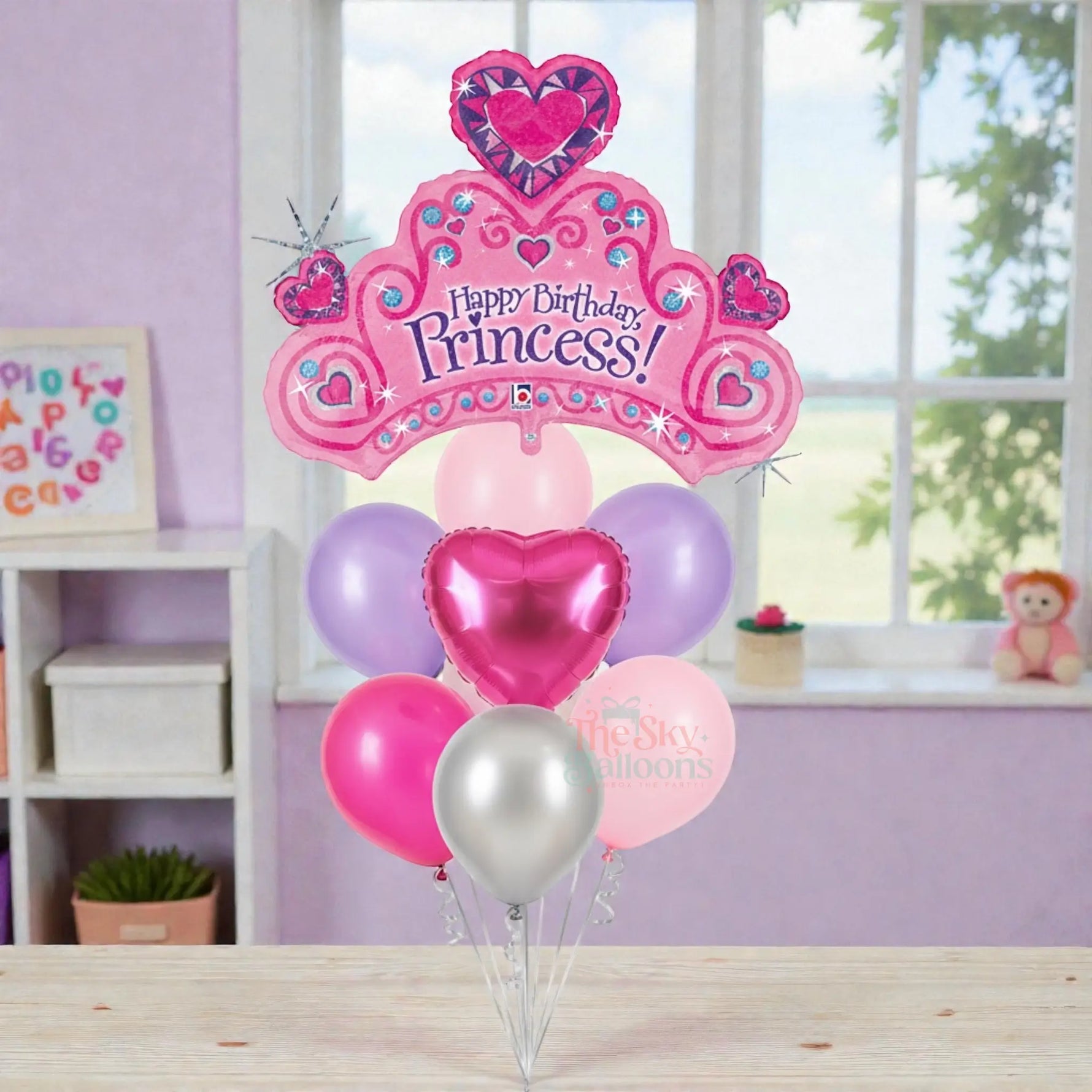 Pink 'Happy Birthday Princess!' balloon with heart shapes in a room setting.