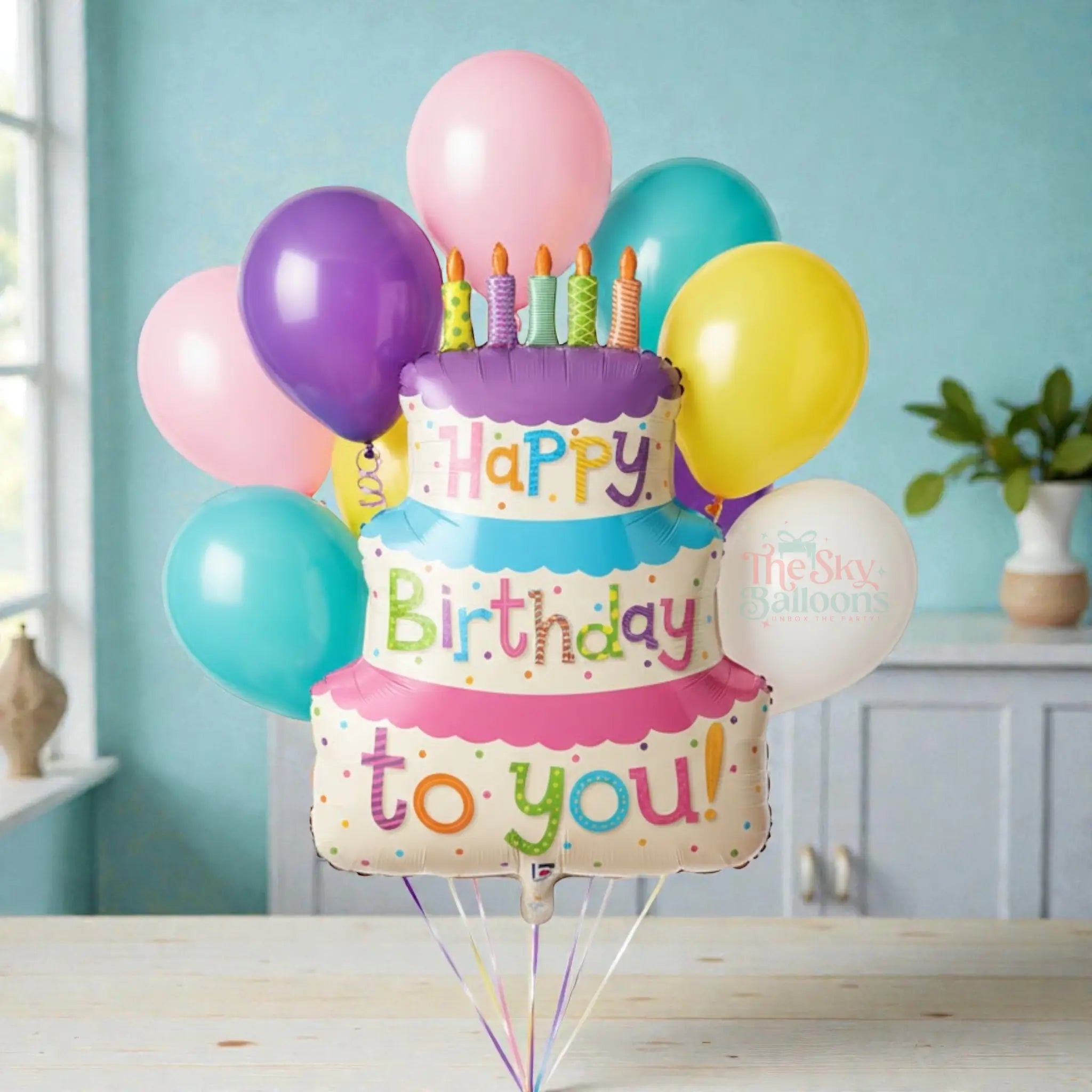 Colorful birthday-themed balloons with a cake-shaped balloon and candles on a white background.
