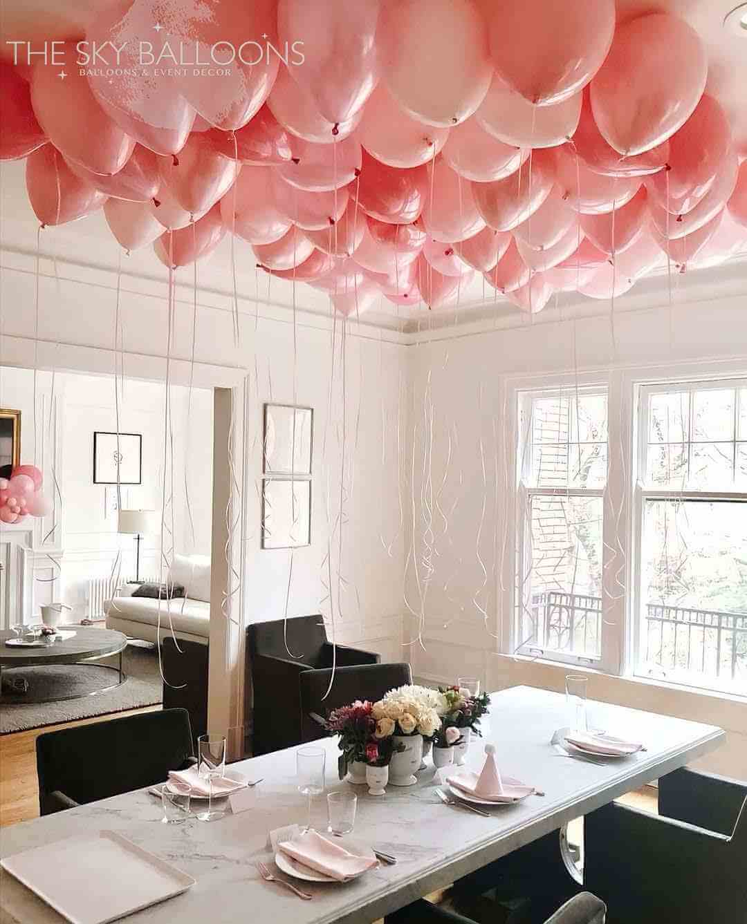 A room with the ceiling decorated with pink pre-inflated balloons creating a festive atmosphere.