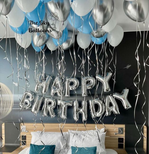 A 'Happy Birthday' balloon arrangement featuring silver and blue balloons along with a banner.