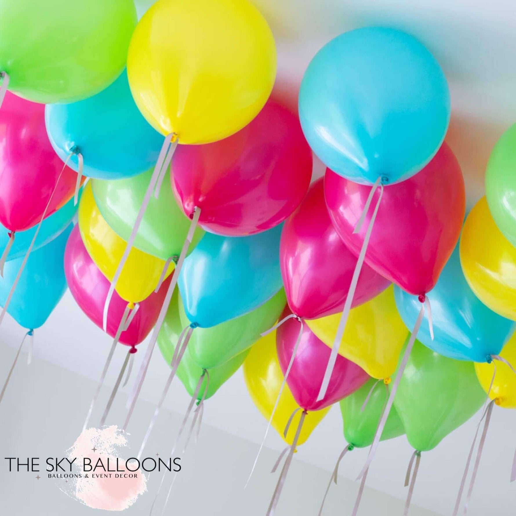 A cluster of brightly colored helium-filled ceiling balloons, including shades of blue, pink, green, yellow, and red.