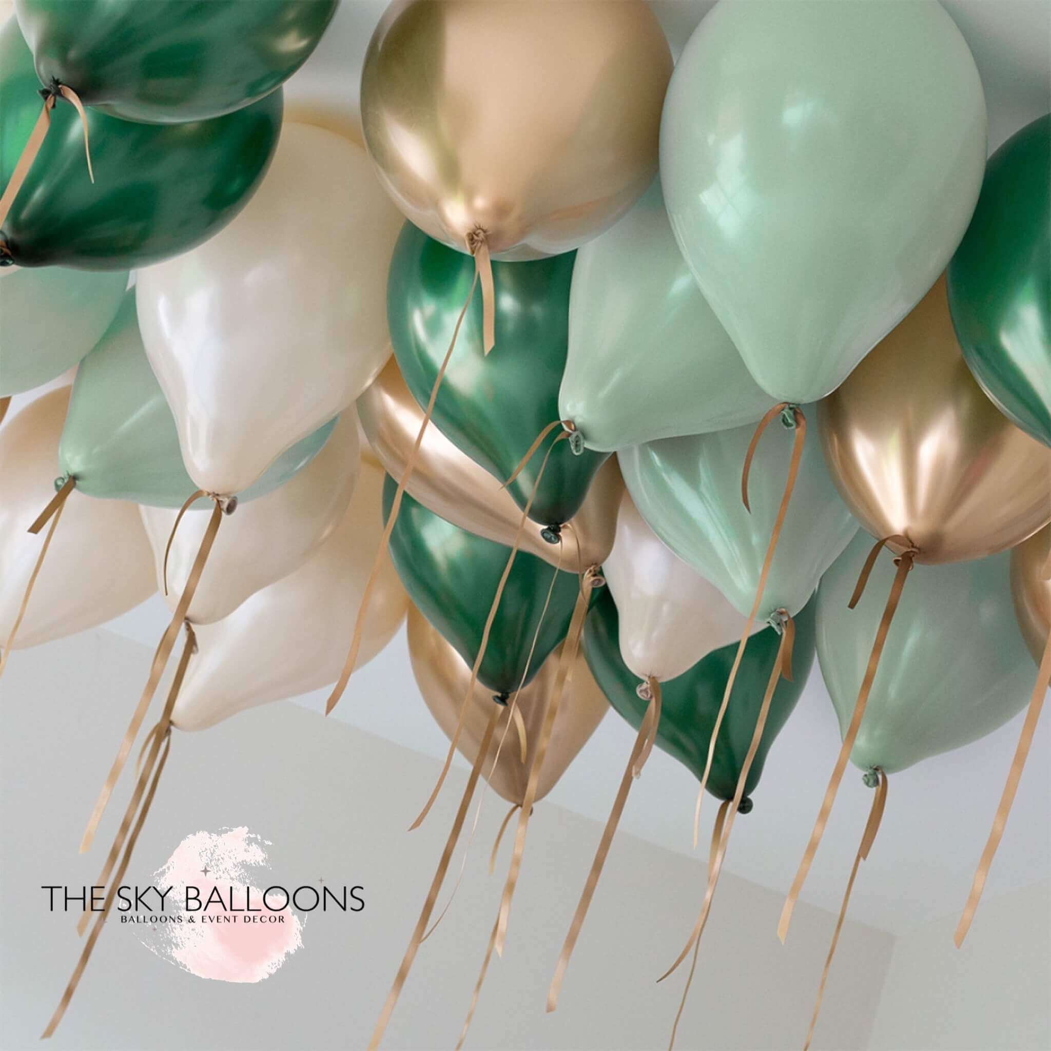 A cluster of helium-filled ceiling balloons in forest green, gold, and white colors, attached to strings.