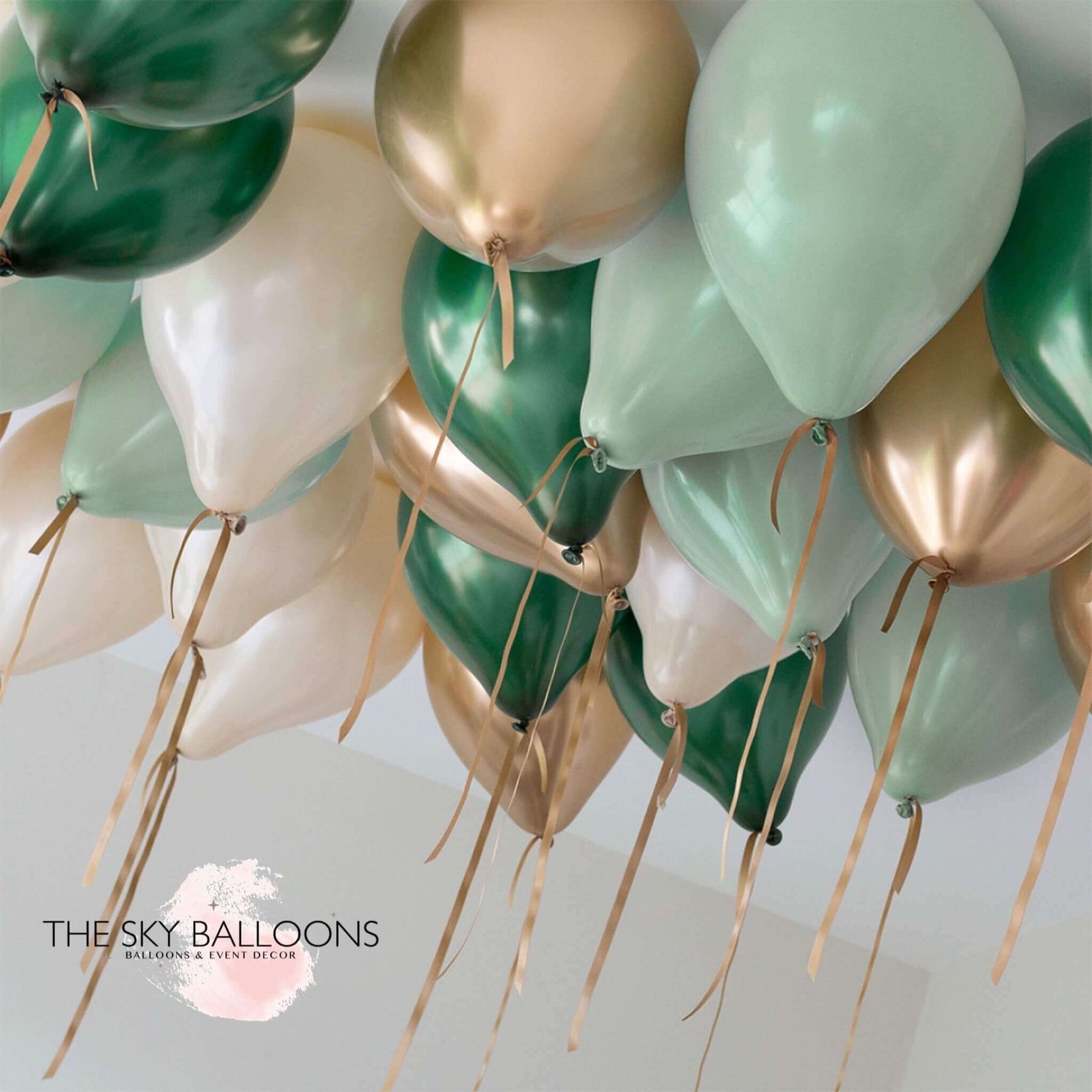 A cluster of helium-filled ceiling balloons in forest green, gold, and white colors, attached to strings.
