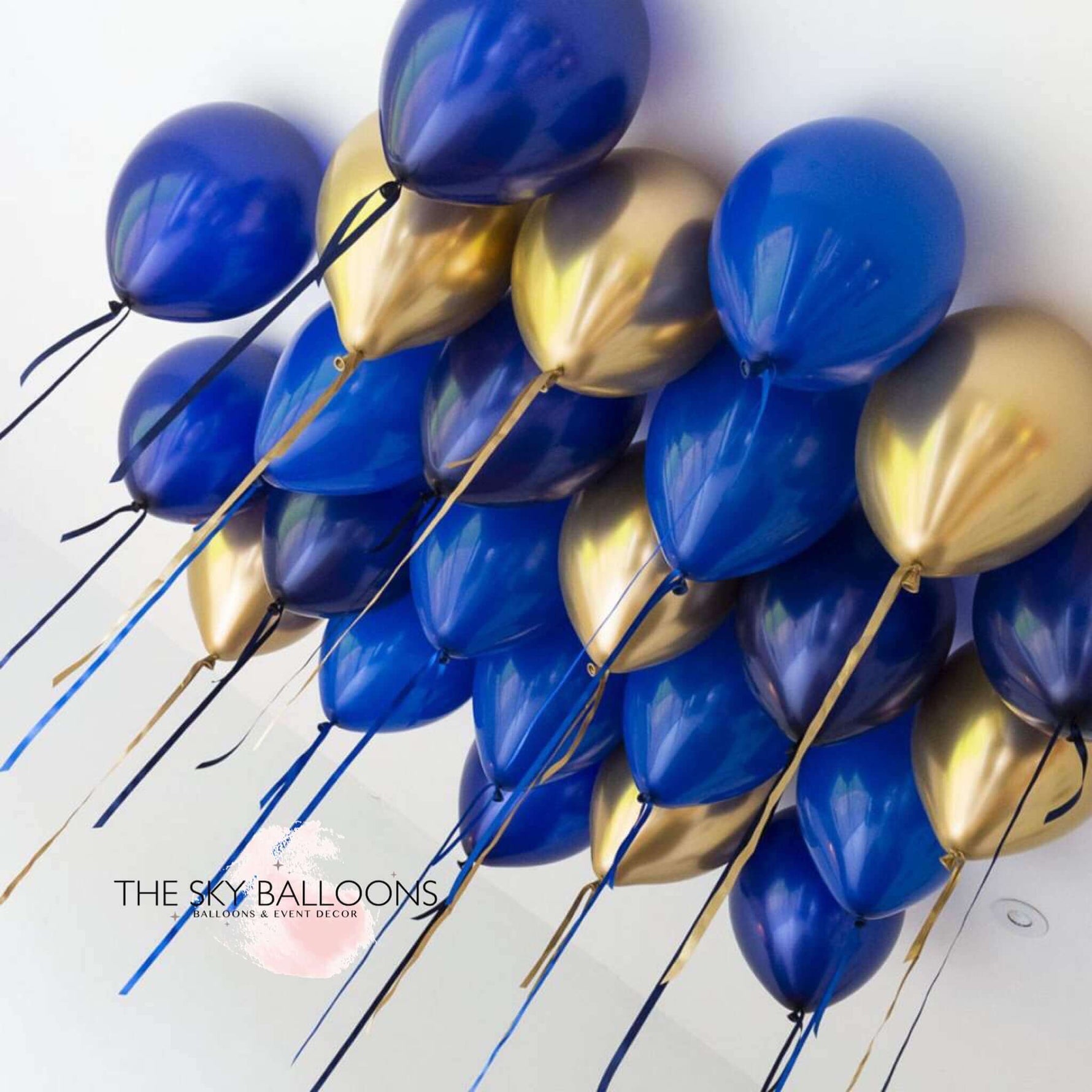 A cluster of navy blue and gold helium-filled ceiling balloons tied with strings, displayed against a white background.