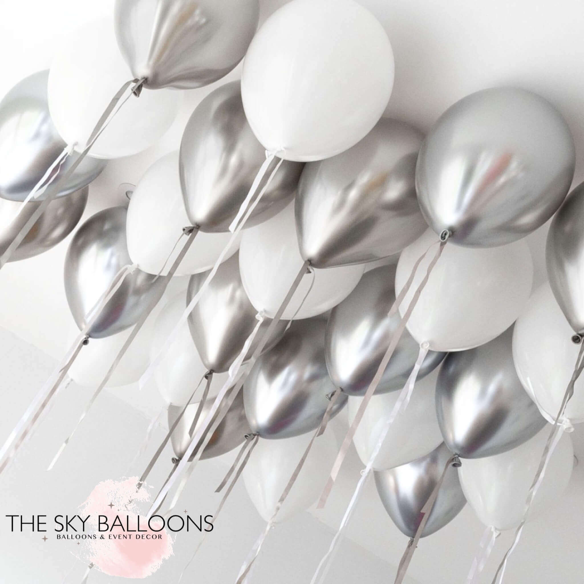 A cluster of inflated helium balloons in white and silver colors, arranged for ceiling decoration.