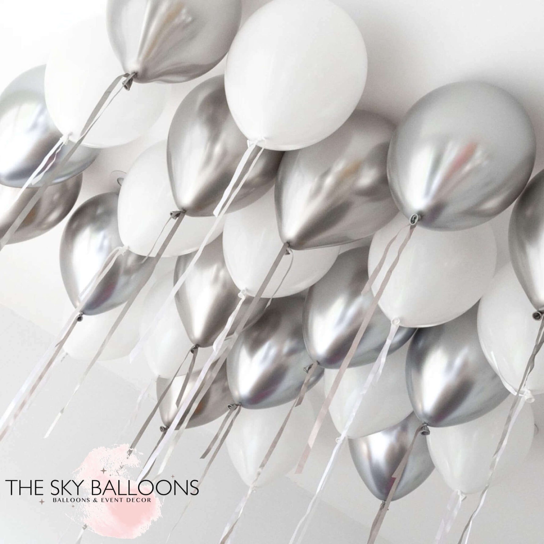 A cluster of inflated helium balloons in white and silver colors, arranged for ceiling decoration.