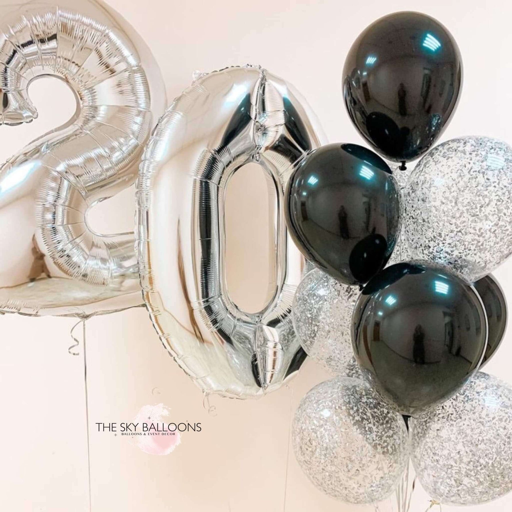 A set of balloons including silver number balloons and black latex and confetti balloons, displayed by THE SKY BALLOONS.