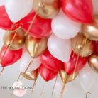 A cluster of inflated balloons in red, white, and gold colors, attached to strings, presumably intended for ceiling decoration.